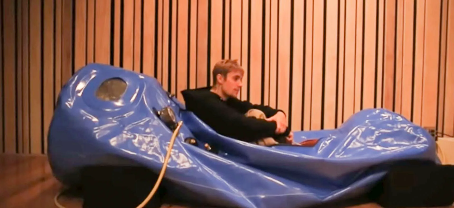 Interior view of a medical-grade hyperbaric oxygen therapy chamber with a patient breathing through a 100% oxygen mask.